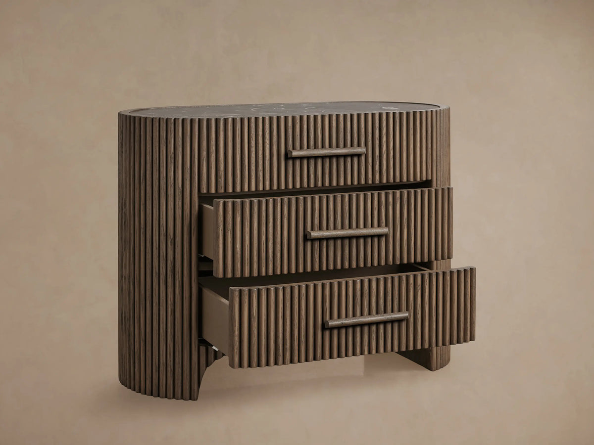 Astor Nightstand: Dark brown oak with reeding, curved sides, 3 drawers with integrated wood pulls, dark marble top.