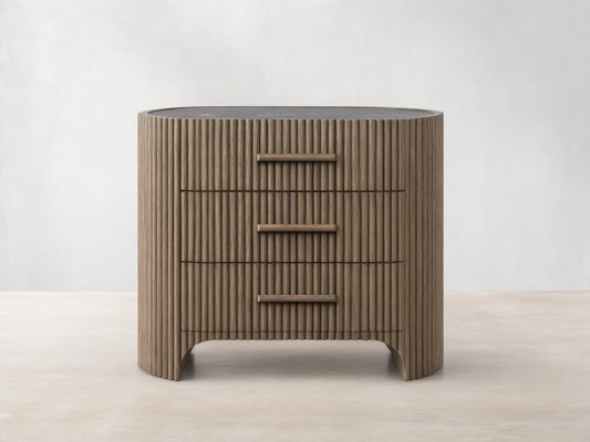 Astor Nightstand: Dark brown oak with reeding, curved sides, 3 drawers with integrated wood pulls, dark marble top.