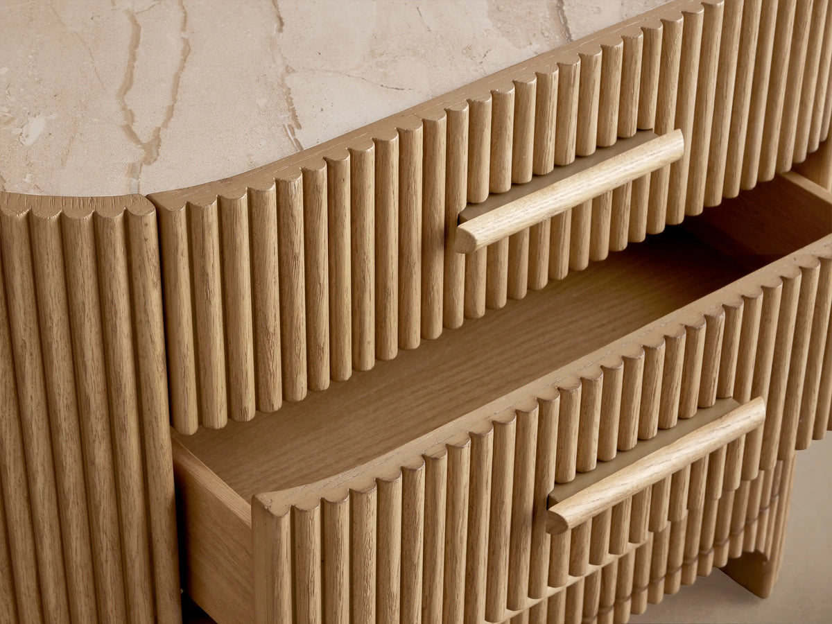 Light oak Astor Nightstand with vertical reeding, light marble top, and 3 drawers with matching wooden pulls, angled.
