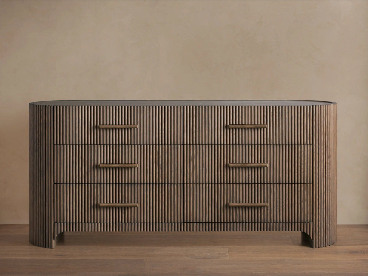 Astor Six-Drawer Dresser with oak veneer and solid oak reeding, featuring three drawers with stone pulls, set in a minimalist room.