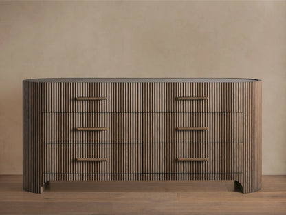Astor Six-Drawer Dresser with oak veneer and solid oak reeding, featuring three drawers with stone pulls, set in a minimalist room.