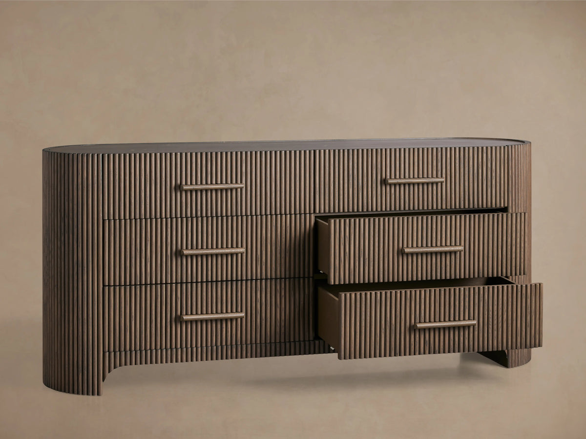 Astor Six-Drawer Dresser with oak veneer and solid oak reeding, featuring three drawers with stone pulls, set in a minimalist room.