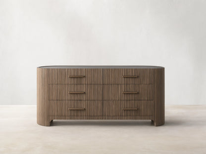 Astor Six-Drawer Dresser with oak veneer and solid oak reeding, featuring three drawers with stone pulls, set in a minimalist room.