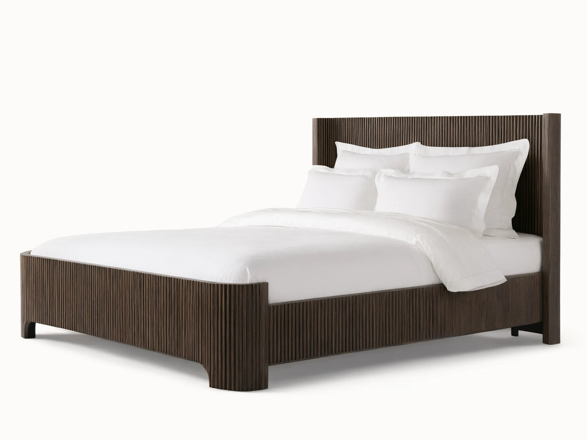Astor Bed with solid oak reeding, dark finish. White bedding with pillows contrasts the vertical slats, set on wooden floor.