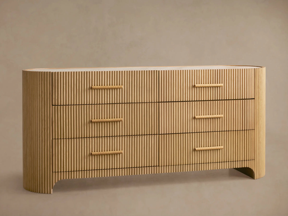 Astor Six-Drawer Dresser in light oak with vertical reeding texture and natural marble top. One drawer is open.