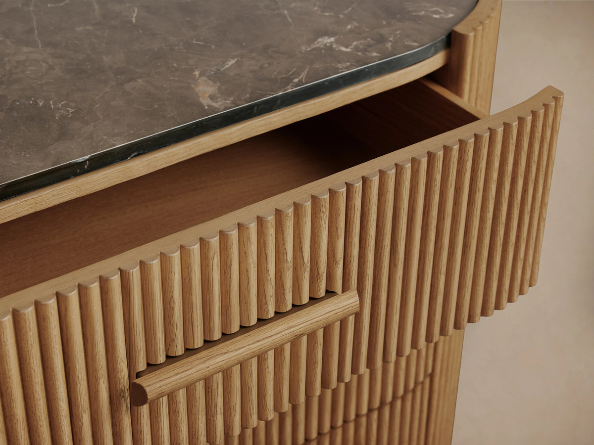 Astor Six-Drawer Dresser made of oak veneer with horizontal reeding, natural marble top. Two drawers partially open.