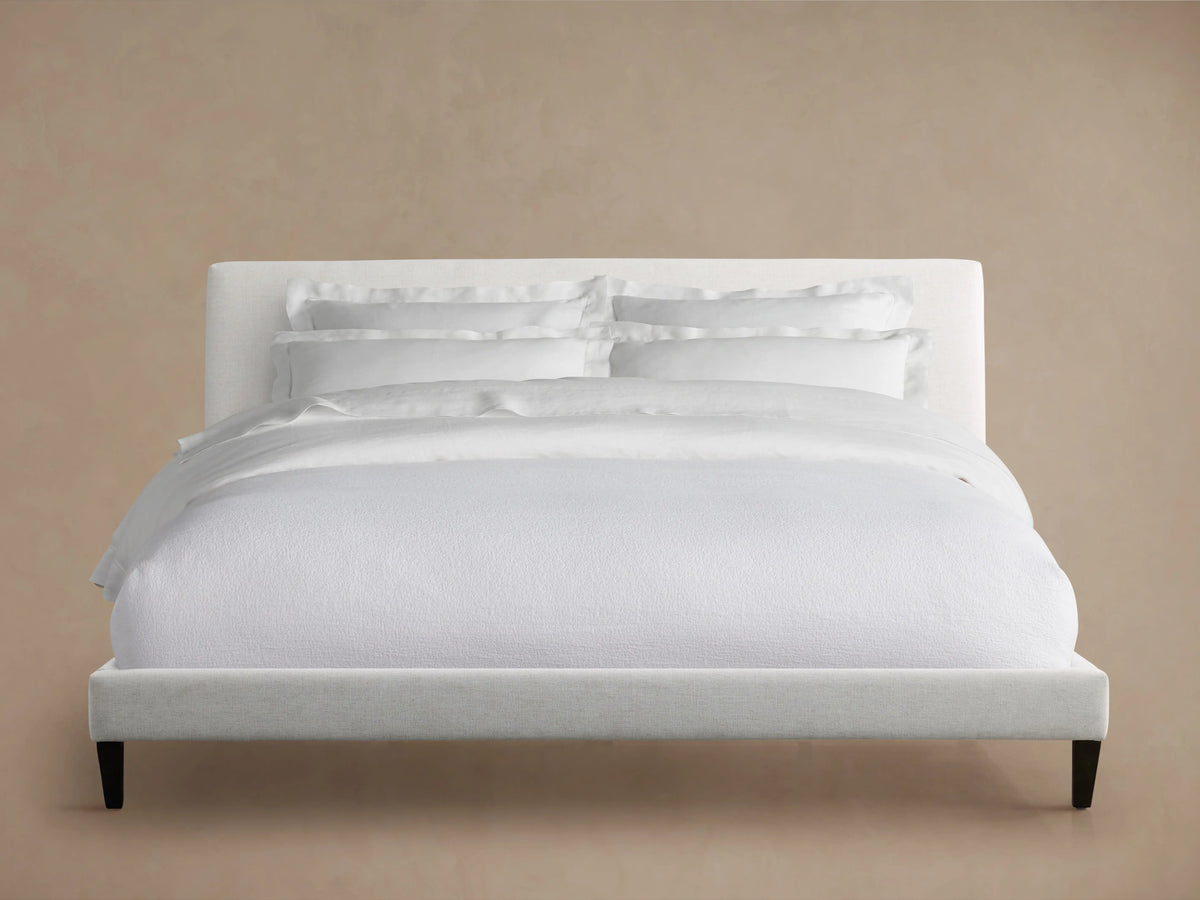 Beck Bed headboard, close-up view showing the soft, durable Crypton® Nomad Snow fabric in a light cream color against a beige wall.