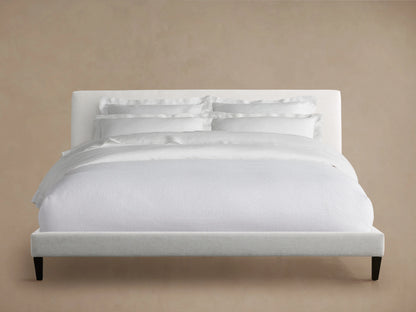 Beck Bed headboard, close-up view showing the soft, durable Crypton® Nomad Snow fabric in a light cream color against a beige wall.