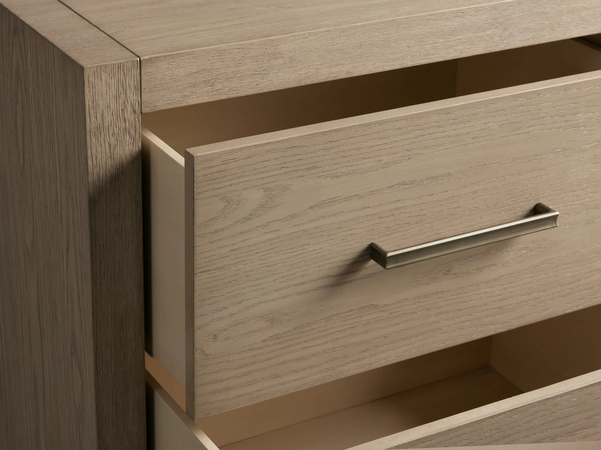 Bodhi Closed Nightstand, close-up of light wire-brushed oak wood with visible grain, upper drawer slightly ajar, champagne brass handle.