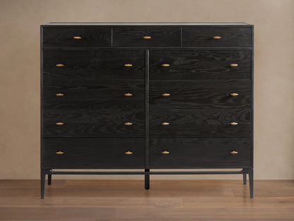Brock Eleven-Drawer Dresser made of dark-stained ash wood with brass handles, showcasing a sleek, handcrafted silhouette on a wood floor.