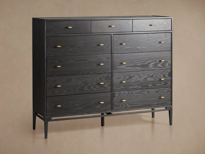 Brock Eleven-Drawer Dresser made of dark-stained ash wood with brass handles, showcasing a sleek, handcrafted silhouette on a wood floor.