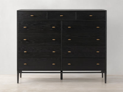 Brock Eleven-Drawer Dresser made of dark-stained ash wood with brass handles, showcasing a sleek, handcrafted silhouette on a wood floor.