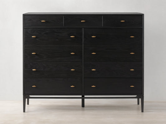 Brock Eleven-Drawer Dresser made of dark-stained ash wood with brass handles, showcasing a sleek, handcrafted silhouette on a wood floor.