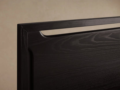 Ebony-colored Brock Bed with a high solid ash wood headboard and white bedding, set on a wooden floor in a beige room.