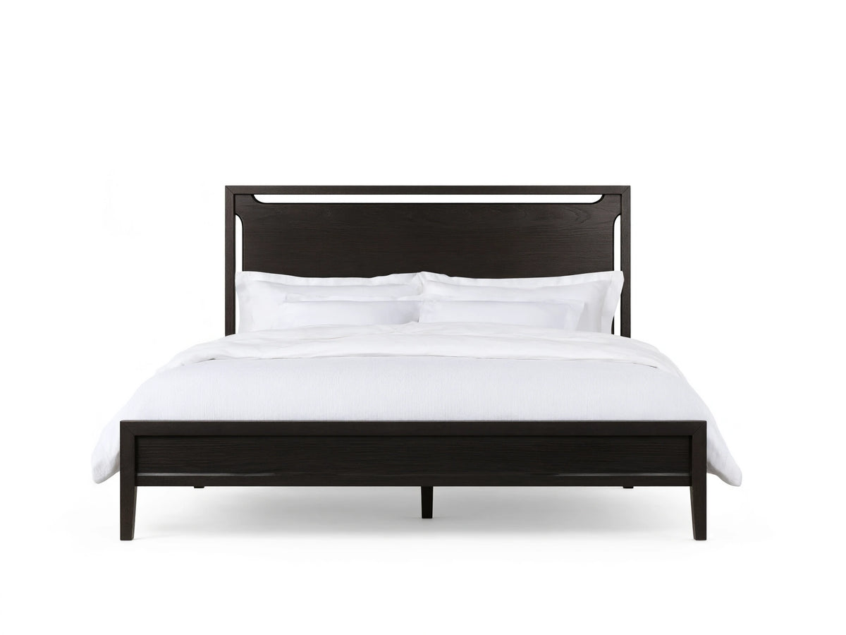 Ebony-colored Brock Bed with a high solid ash wood headboard and white bedding, set on a wooden floor in a beige room.