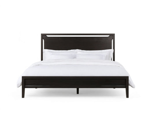 Ebony-colored Brock Bed with a high solid ash wood headboard and white bedding, set on a wooden floor in a beige room.