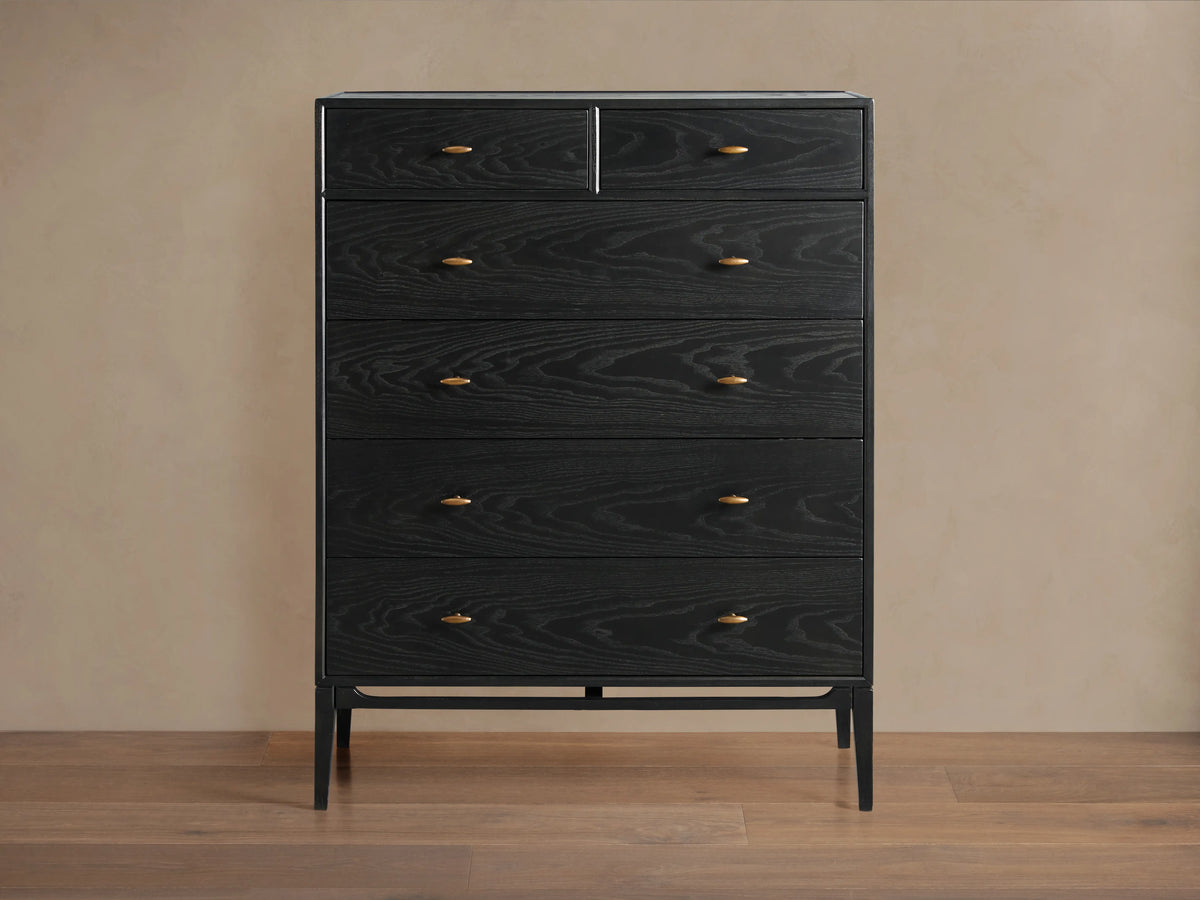 Brock Six-Drawer Dresser made of dark stained ash wood with brass handles, set against a light brown background.