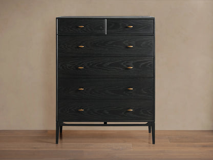 Brock Six-Drawer Dresser made of dark stained ash wood with brass handles, set against a light brown background.