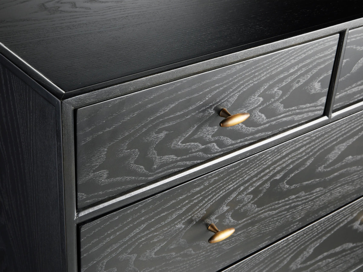 Brock Six-Drawer Dresser made of dark stained ash wood with brass handles, set against a light brown background.