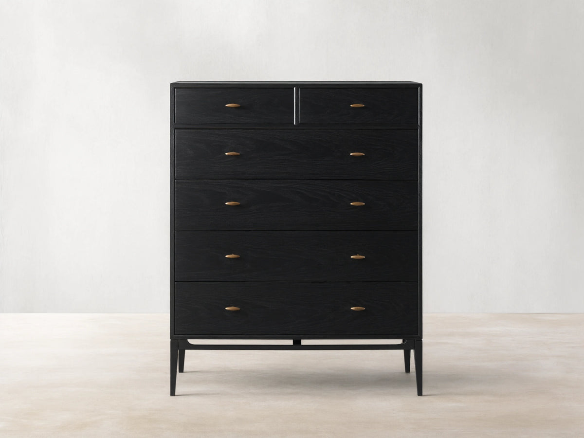 Brock Six-Drawer Dresser made of dark stained ash wood with brass handles, set against a light brown background.