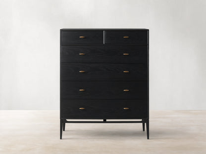 Brock Six-Drawer Dresser made of dark stained ash wood with brass handles, set against a light brown background.