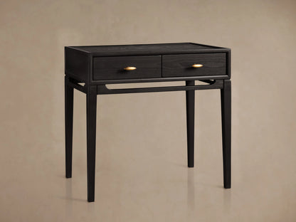 Brock Nightstand in ebony-stained ash wood with two drawers, brass hardware, and tapered legs, set against a beige background.