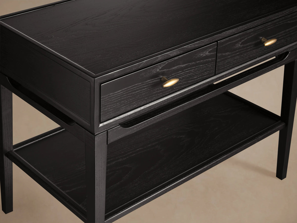 Brock Nightstand in rich ebony with two drawers featuring brushed brass hardware. Lower shelf visible, set on four sturdy legs.