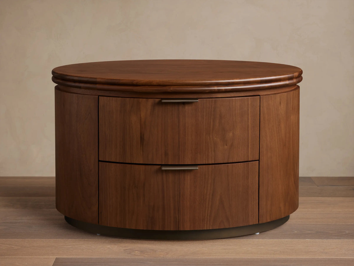 Front view of the walnut Caden Wood Oval Nightstand, featuring two drawers with antique bronze edge-pull hardware.