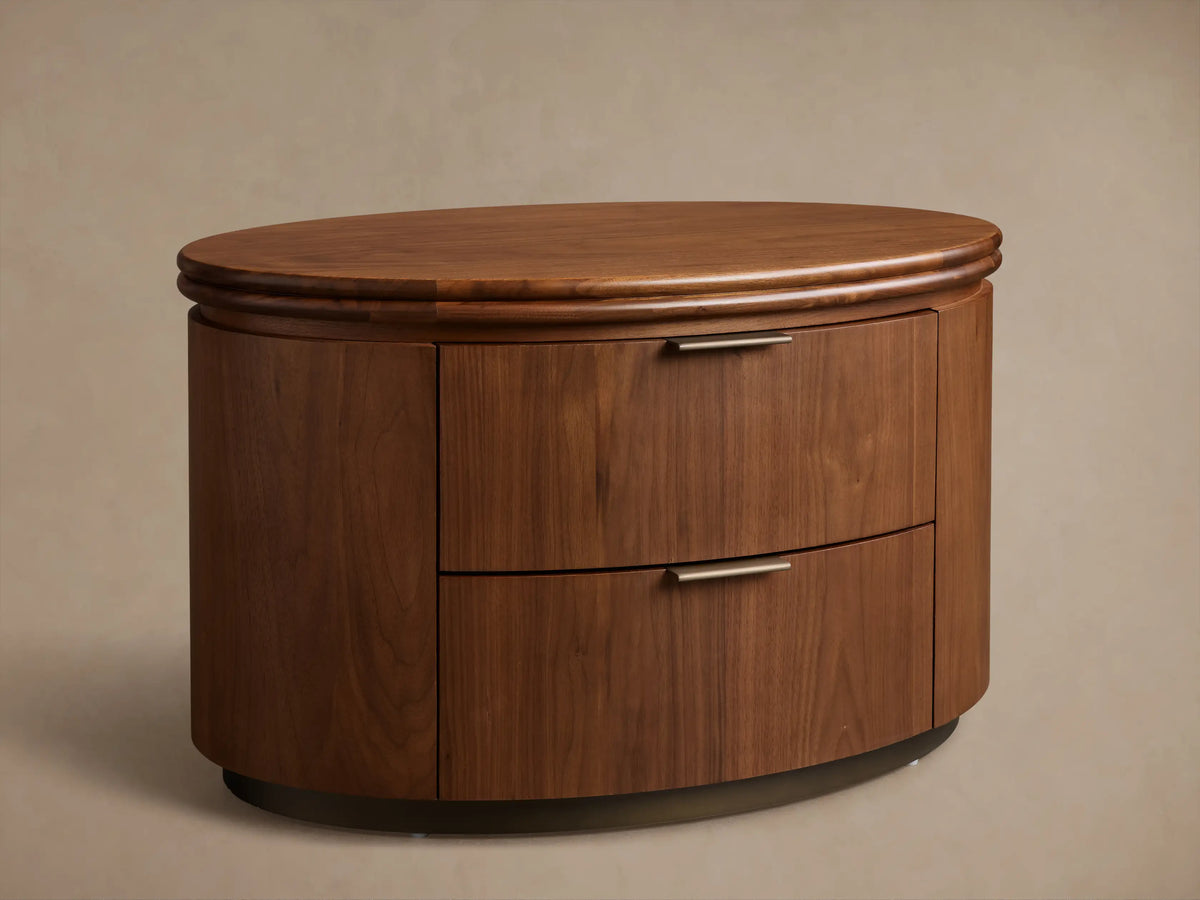 Front view of the walnut Caden Wood Oval Nightstand, featuring two drawers with antique bronze edge-pull hardware.