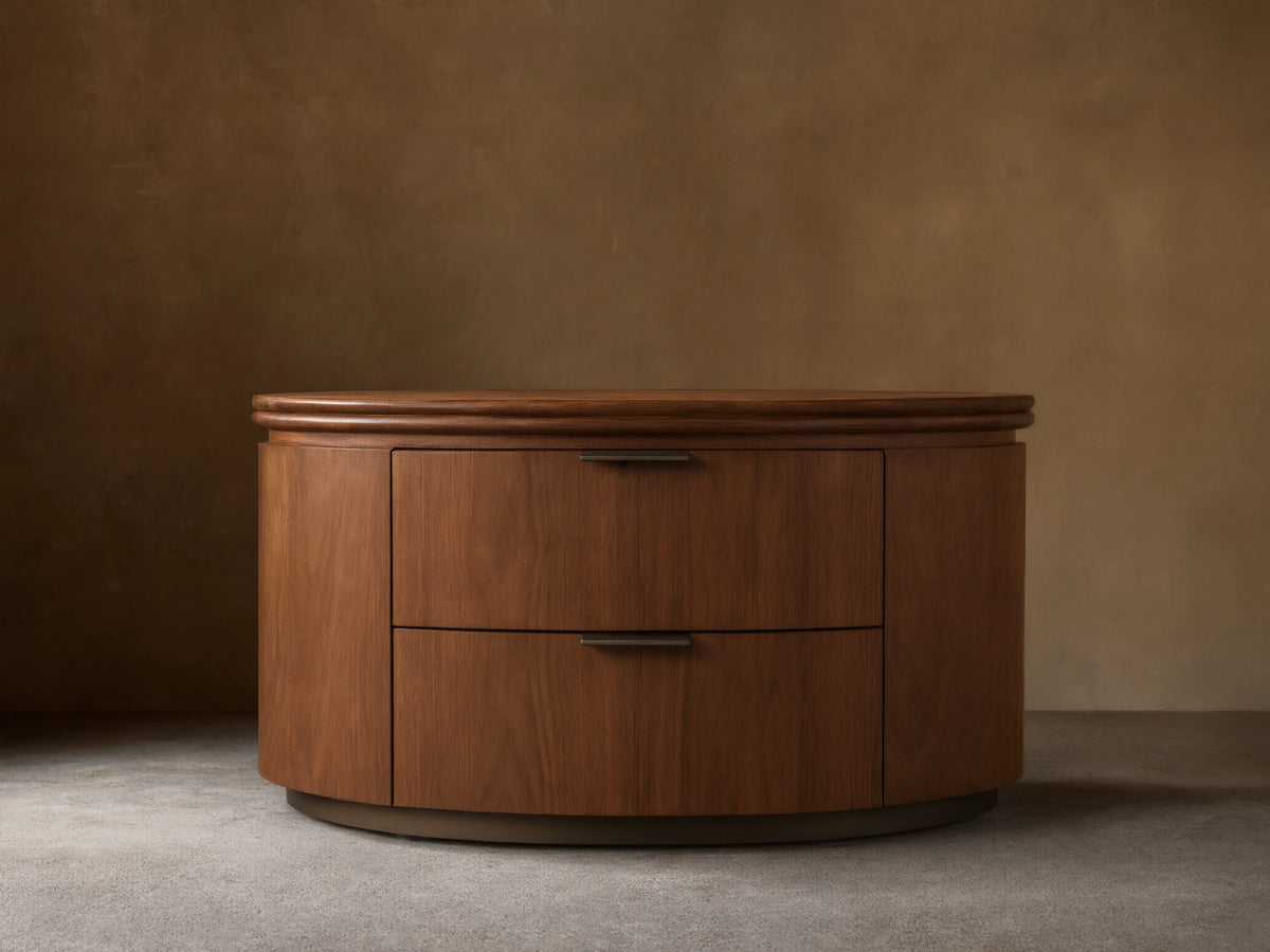 Front view of the walnut Caden Wood Oval Nightstand, featuring two drawers with antique bronze edge-pull hardware.