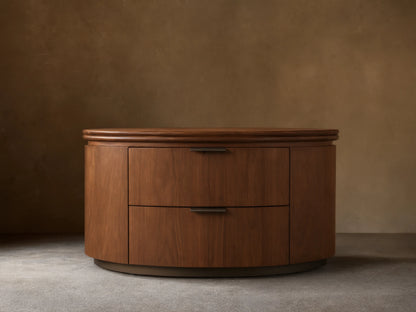 Front view of the walnut Caden Wood Oval Nightstand, featuring two drawers with antique bronze edge-pull hardware.