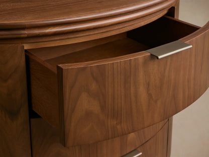 Front view of the glossy walnut Caden Wood Oval Nightstand, featuring three drawers with antique bronze edge-pull hardware and a plinth base.