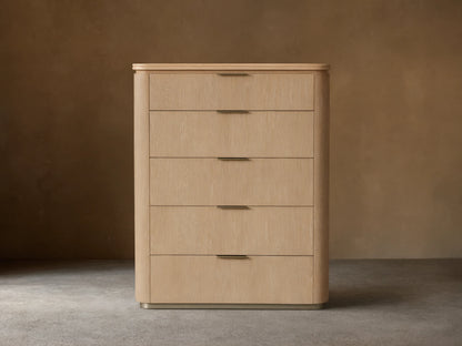 Caden Five-Drawer Dresser with sand oak veneer, rounded edges, white stone top, and five drawers with pewter edge-pull hardware.