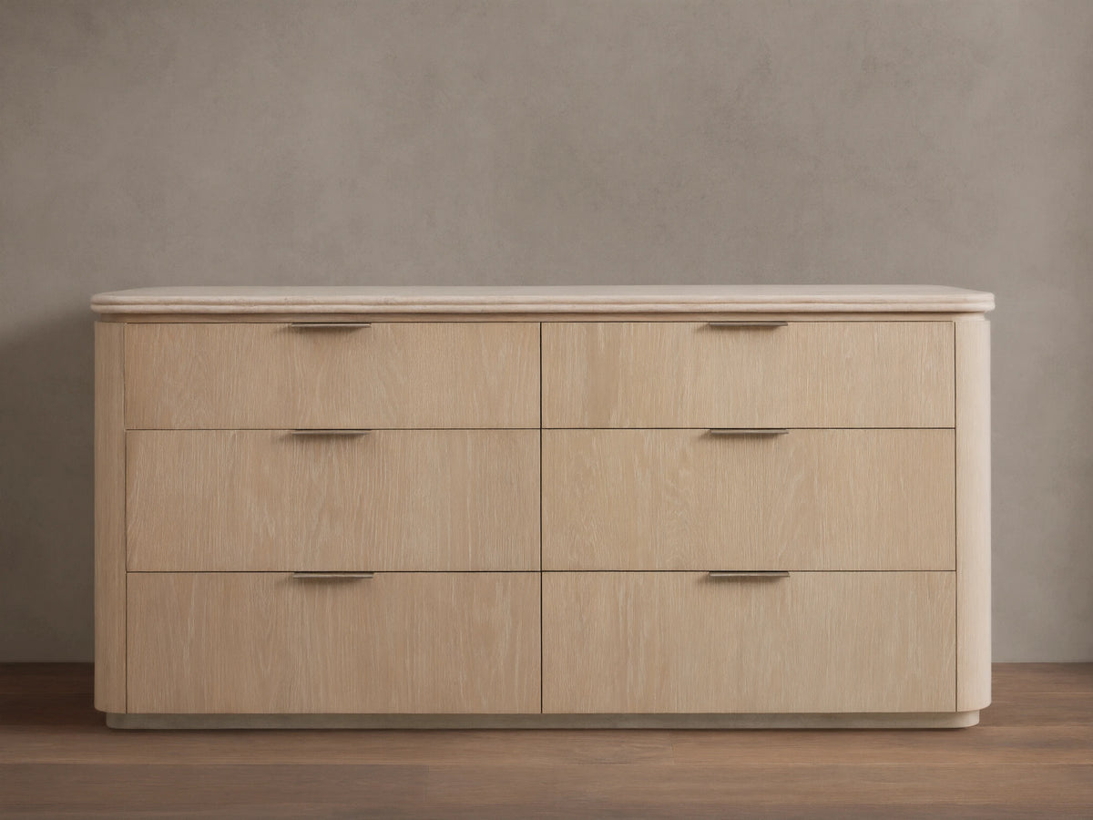 Caden Six-Drawer Dresser in sand finish oak veneer, with a light stone top, pewter edge-pulls, and rounded corners.