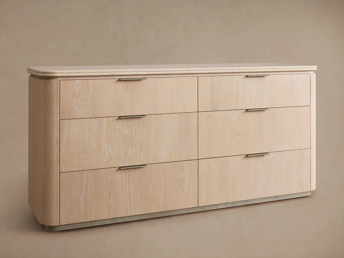 Caden Six-Drawer Dresser in sand finish oak veneer, with a light stone top, pewter edge-pulls, and rounded corners.