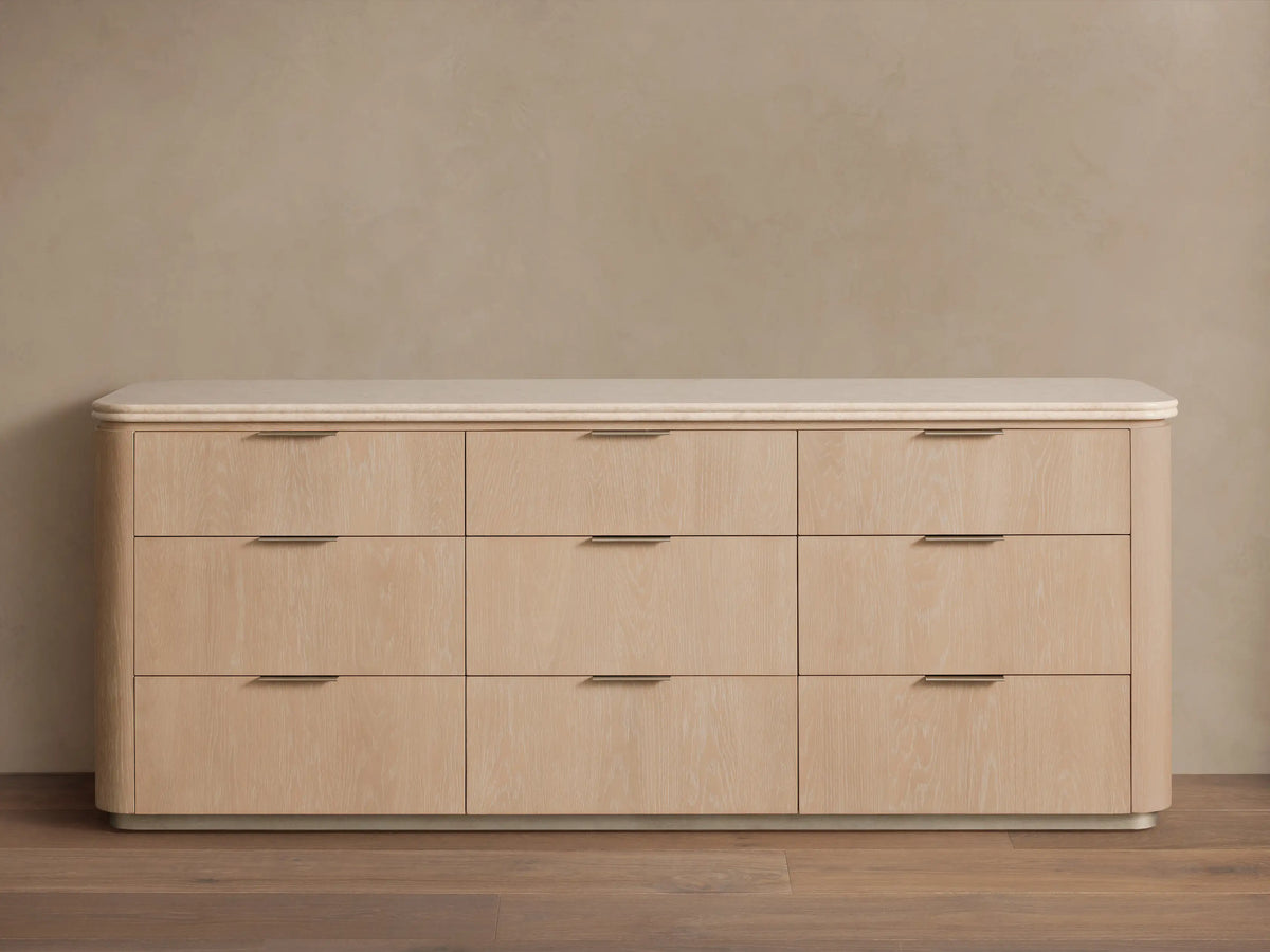 Caden Nine-Drawer Dresser: light sand oak veneer with rounded edges, a light stone top, and pewter hardware.