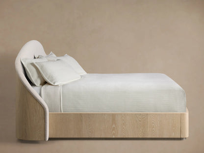 Close-up of the cream textured bouclé fabric on the curved headboard of the Caden Bed, with a light wood frame edge.