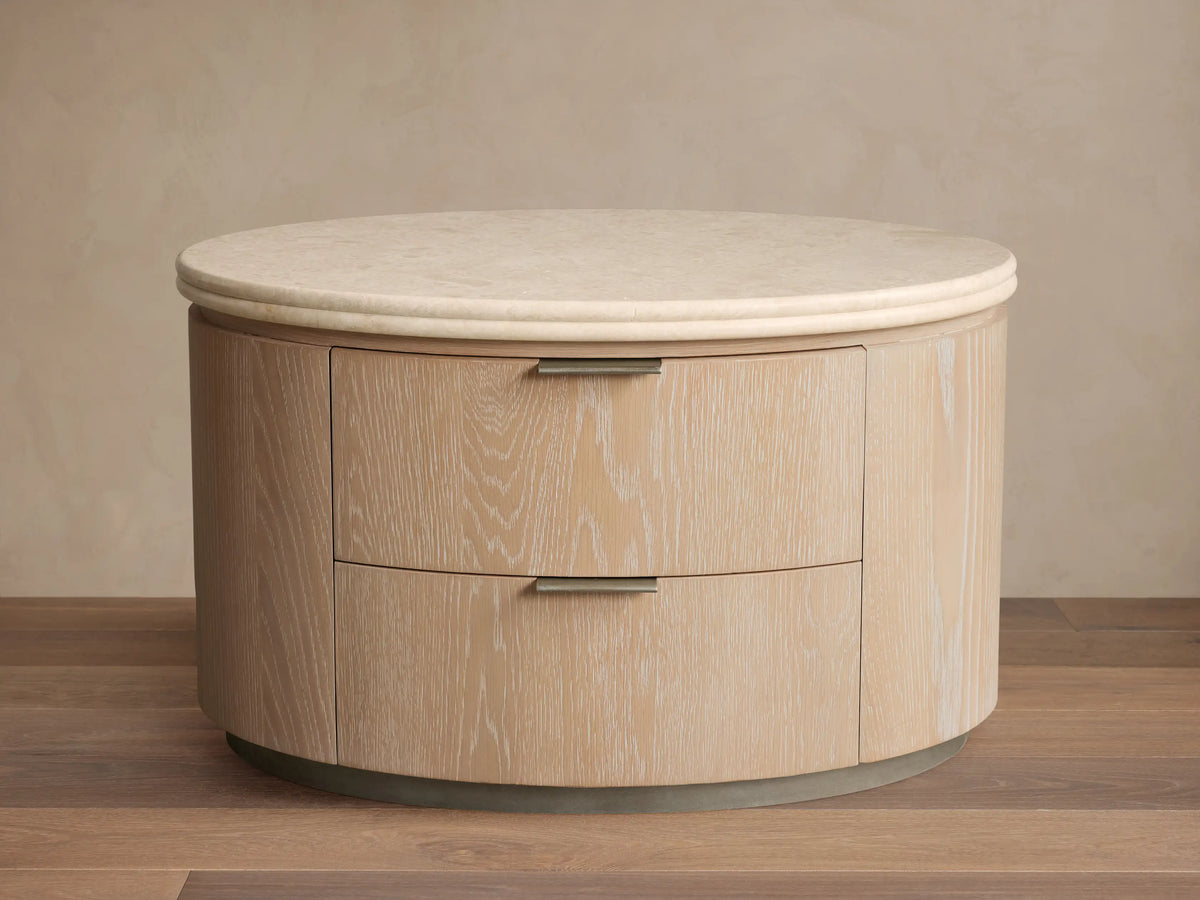 Caden Oval Nightstand in light sand oak veneer with visible grain, two drawers with pewter pulls, and a cream stone top.