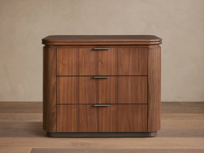 Front view of Caden Wood Nightstand. Walnut veneer with subtle sheen, rounded top, 3 drawers with antique bronze edge pulls.