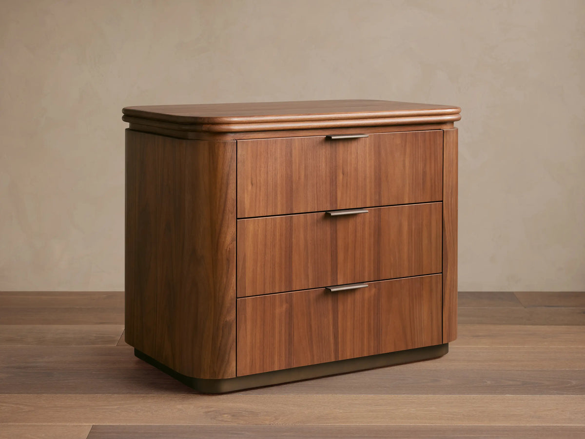 Front view of Caden Wood Nightstand. Walnut veneer with subtle sheen, rounded top, 3 drawers with antique bronze edge pulls.