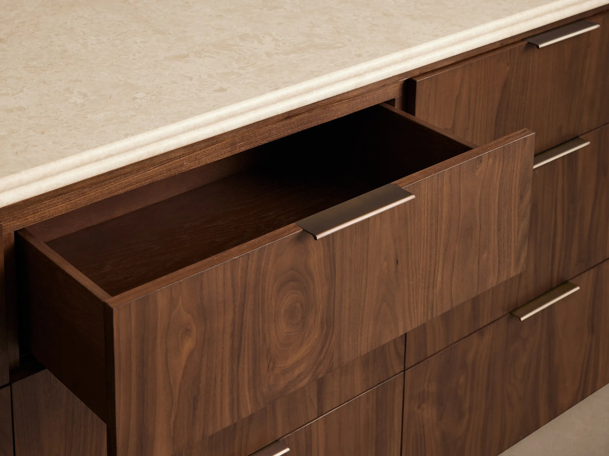Caden Nine-Drawer Dresser in dark walnut wood veneer with light stone top, 9 drawers, rounded sides, antique bronze edge pulls.