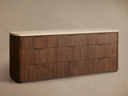 Close-up of Caden Nine-Drawer Dresser, light walnut wood & beige speckled stone top. One drawer is open, revealing dark interior & bronze handle.