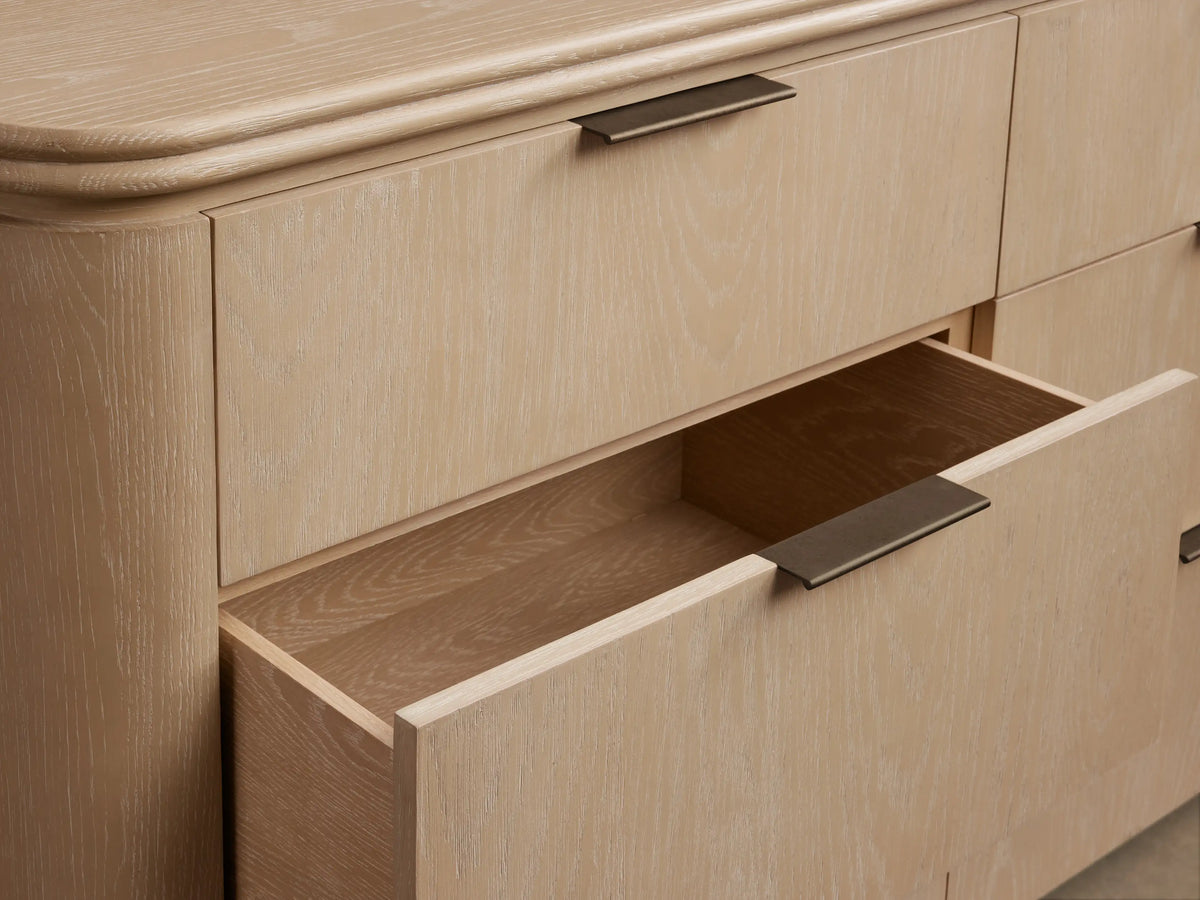 Front view of the sand finish Caden Wood Nine-Drawer Dresser with nine drawers, dark edge-pull hardware, and a rounded top.