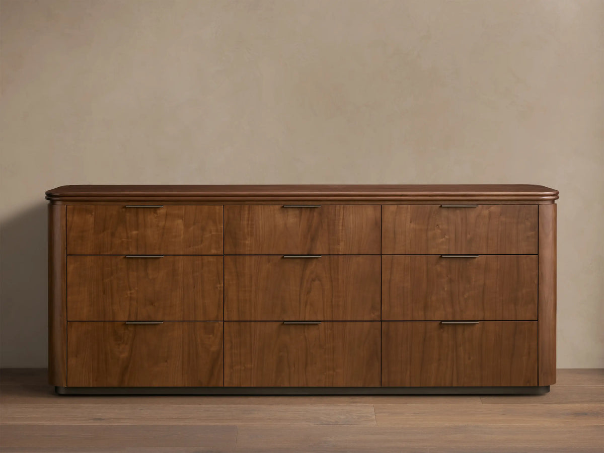 Front view of the walnut Caden Wood Nine-Drawer Dresser™ with nine drawers, antique bronze edge-pull hardware, and a rounded top.