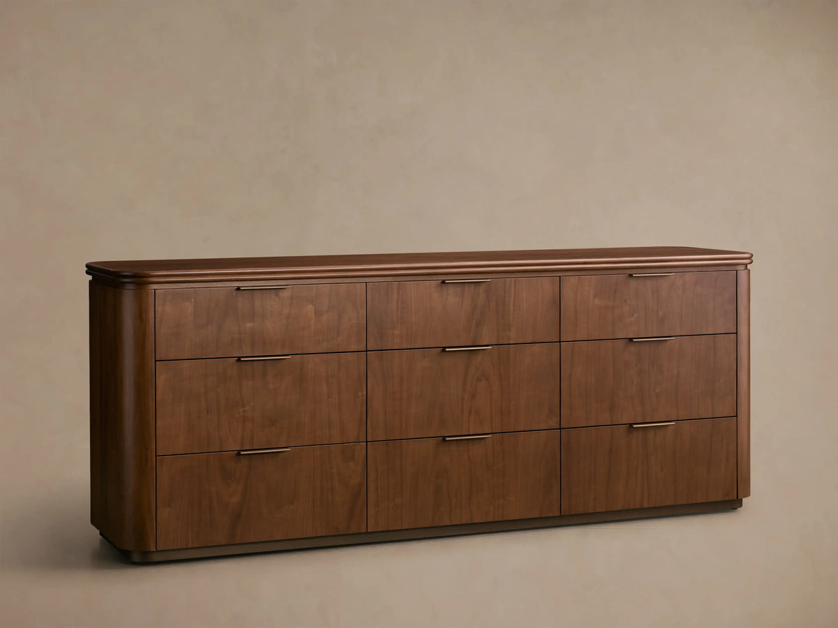 Front view of the walnut Caden Wood Nine-Drawer Dresser™ with nine drawers, antique bronze edge-pull hardware, and a rounded top.