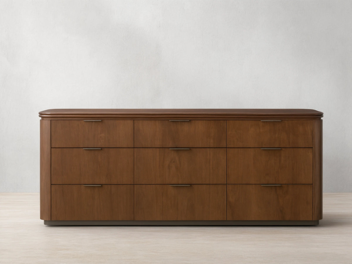 Front view of the walnut Caden Wood Nine-Drawer Dresser™ with nine drawers, antique bronze edge-pull hardware, and a rounded top.