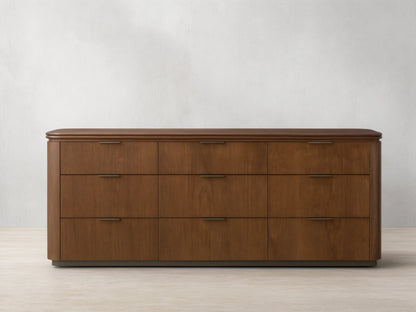 Front view of the walnut Caden Wood Nine-Drawer Dresser™ with nine drawers, antique bronze edge-pull hardware, and a rounded top.