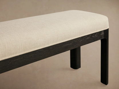 Calista Bench, full front view. Light cream upholstered top, dark wood frame, on a wooden floor against a neutral wall.