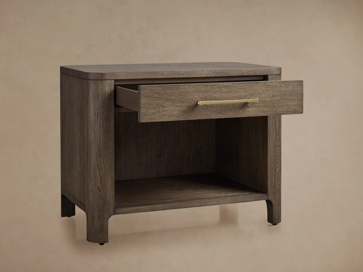 Calista Open Nightstand made of veneered oak with a satin sheen. A partially open drawer with gold hardware is visible.