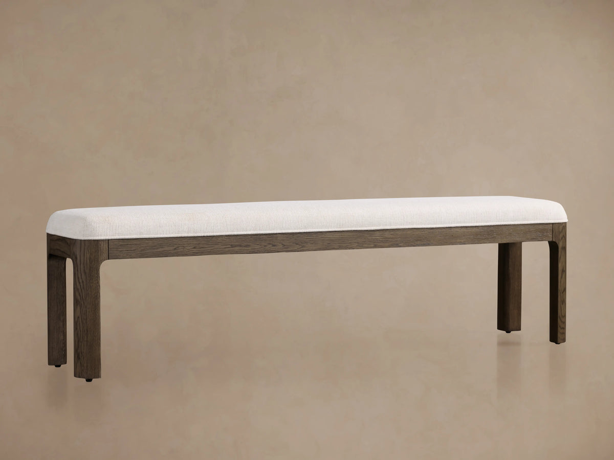 Calista Bench with white cushioned seat, dark oak legs, and minimal design against a plain beige background.